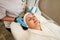 Beautiful woman receiving facial microcurrent treatment from beautician in beauty wellness salon