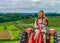 Beautiful woman on a red agricultural tractor, green field, landscape of meadow with grass Upstate New York