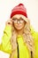 Beautiful woman in red christmas cap and yellow hoodie keeps puts on eye glasses, isolated portrait.