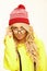 Beautiful woman in red christmas cap and yellow hoodie keeps puts on eye glasses, isolated portrait.