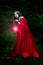 Beautiful woman with red cloak and lantern in the woods