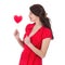 Beautiful woman in red dress eagers a red heart-shaped lollipop