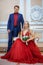 A beautiful woman in a red dress with a man sitting in a chair, the bride and groom, happy newlyweds