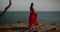 Beautiful woman in red dress on the sea shore cliff
