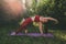 Beautiful woman in red leggings and a top practicing yoga in a city park