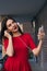 beautiful woman with red lipstick in red dress uses phone and earphones