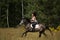 Beautiful woman riding gray horse in the forest