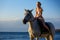 Beautiful woman riding a horse on the sea background, entertainment concept
