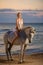 Beautiful woman riding a horse on the sea background, entertainment concept