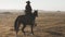 Beautiful woman riding horse at sunrise in field. Young cowgirl at brown horse