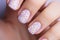 Beautiful woman\\\'s fingernails with white spring flowers on pastel violet base nail art design