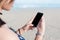 Beautiful woman\'s hand using smart phone at beach.