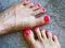 Beautiful woman& x27;s neon pink nails with beautiful pedicure. Female feet with bright pedicure on grey concrete