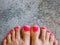 Beautiful woman& x27;s neon pink nails with beautiful pedicure. Female feet with bright pedicure on grey concrete