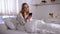 Beautiful woman scrolling smartphone, sitting in bed in morning, social media