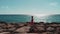 Beautiful woman silhouette walking on rocky sea pier alone. Sea waves hitting rocky beach. Sun road reflection on blue sea with gi