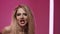 Beautiful woman sings song for a music video in studio on a pink background.