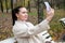 beautiful woman sits on a bench in the park. middle aged woman taking a selfie on the phone in the park