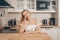 Beautiful woman sits at a table on the background of the kitchen at home. The girl speaks on the phone, food delivery