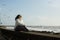 Beautiful  woman sits on the waterfront during the surf and gulls around