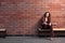 Beautiful woman sitting on a bench on a brick wall background