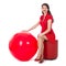 Beautiful woman sitting on footstool holding big red balloon