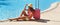 Beautiful woman sitting near pink suitcase near swimming hotel pool area. Travel, summer holidays and vacation concept. Panoramic