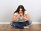 Beautiful woman sitting in new flat on the floor with thinking look in blue ripped jeans. Positive