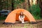 Beautiful woman sitting outside the tent in free alternative vacation camping in the forest. different lifestyle