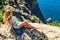 Beautiful woman sitting on a rock near blue sea