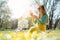 Beautiful woman sitting on a spring meadow picking daisy flower