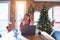 Beautiful woman sitting at the table working with laptop at home around christmas tree Moving away hands palms showing refusal and