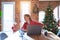 Beautiful woman sitting at the table working with laptop at home around christmas tree Suffering of backache, touching back with