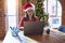 Beautiful woman sitting at the table working with laptop wearing santa claus hat at christmas with serious expression on face