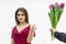 Beautiful woman with snobbish expression, looking with skeptical expression at the bunch of tulips her man gives her.