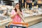 A beautiful woman stands in a large grocery store near a grocery cart and bites a piece of fresh fragrant bread. A woman stands