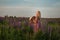 A beautiful woman in a straw hat walks in a field with purple flowers. A walk in nature in the lupin field