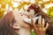 Beautiful woman in a striped t-shirt happily plays with a small husky puppy in the park outdoors