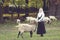 Beautiful woman stroking sheep on a green glade