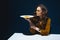 beautiful woman in stylish clothing with unhealthy meat pastry on plate sitting at table with blue