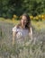 Beautiful woman in sunny day wearing pink dress and sitting in fresh lavander field, enjoying beauty of nature