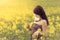 Beautiful woman in sunny summer love looking at rapeseed flower