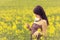 Beautiful woman in sunny summer love looking at rapeseed flower
