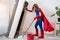 Beautiful woman superhero vacuuming under the bed