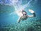 beautiful woman swims underwater, smiling and waves a hand