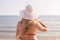 Beautiful woman in a swimsuit and white hat with long blond hair on the seashore. Back view with many moles on the back