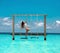 Beautiful woman swinging in the Indian Ocean over tropical landscape, Maldives island background