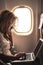 Beautiful woman travel on airplane flight and use a personal laptop computer on board with internet connection to work - digital n