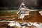 Beautiful woman traveler back standing on rocks in river, wearing hat and poncho, boho travel concept