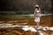 beautiful woman traveler back standing on rocks in river, wearing hat and poncho, boho travel concept